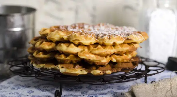 En hög med fluffiga, gyllene frasvåfflor, pudrade med florsocker. Perfekt för ett mysigt fika.