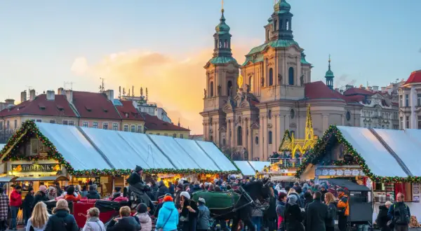 En livlig prag julmarknad med folk, häst och vagn, och en kyrka i bakgrunden.
