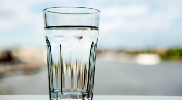 Ett glas med klart vatten står på ett bord. Frågan är om kan man dricka kranvatten i Tyskland?