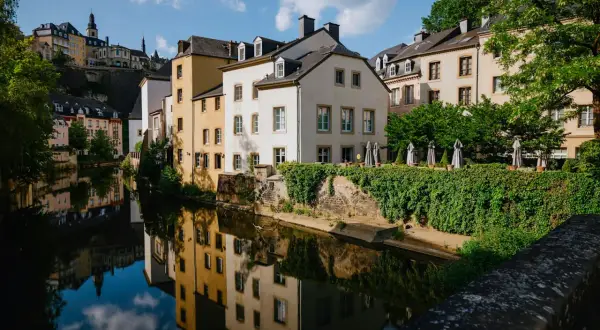 Vackra hus längs en flod i Luxemburgs huvudstad, med speglingar i vattnet.