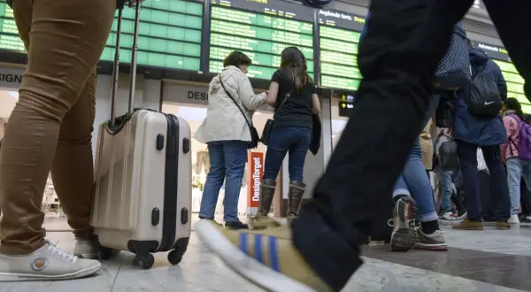 Resenärer med bagage vid en avgångstavla. Kanske dags att fundera på ving av och ombokningsskydd för resan.
