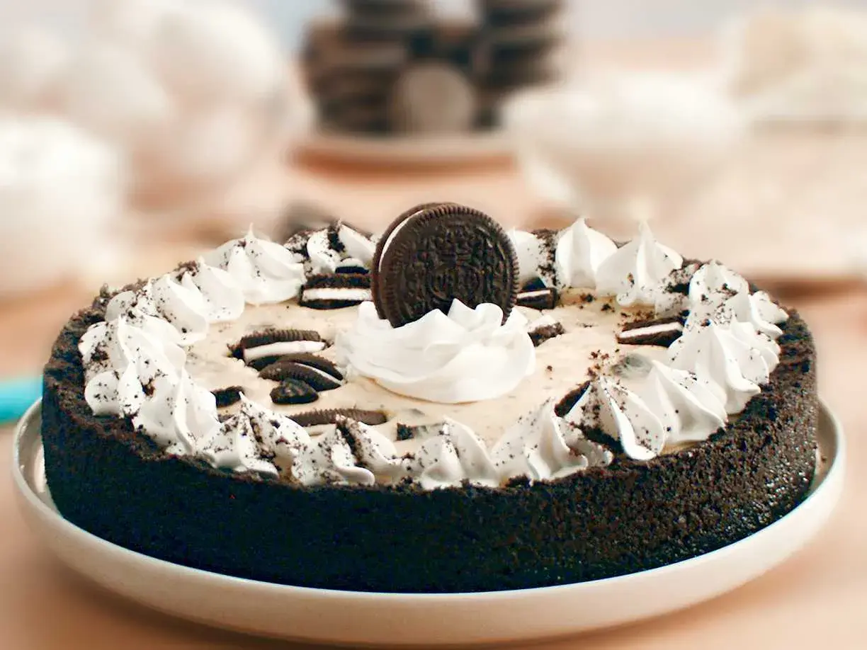 En krämig oreo cheesecake med vispgrädde och krossade oreos.