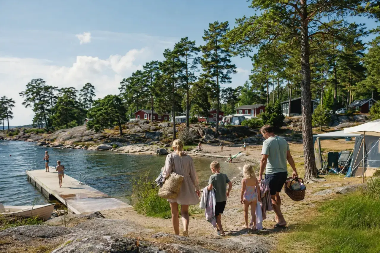 Familj på väg mot vattnet för en härlig sommarsemester med barn. Sol, bad och campingliv vid en svensk sjö.