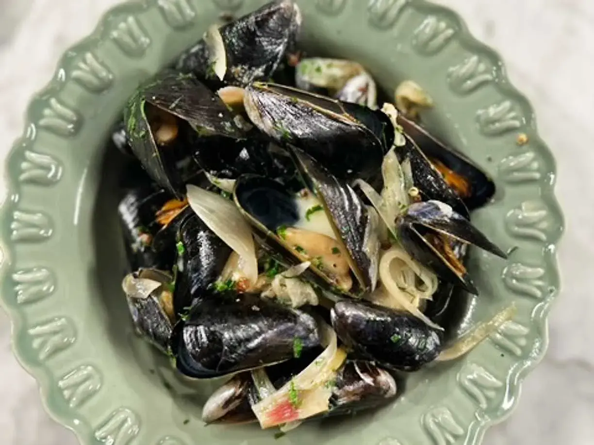 En skål med ångade musslor och lök, perfekt för ett enkelt musslor recept.