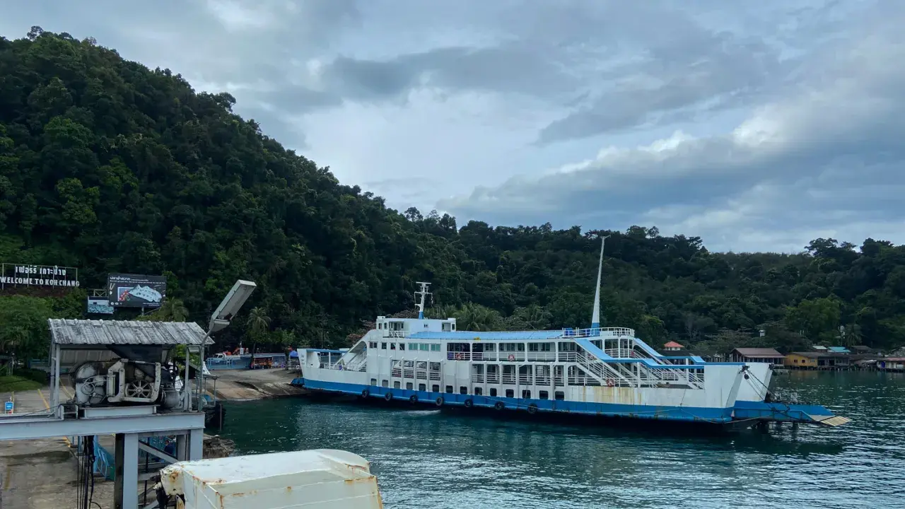 Färja anländer till Koh Chang. Gröna berg och molnigt himmel.