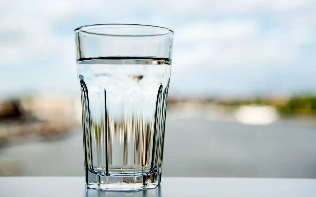 Ett glas med klart vatten står på ett bord. Frågan är om kan man dricka kranvatten i Tyskland?