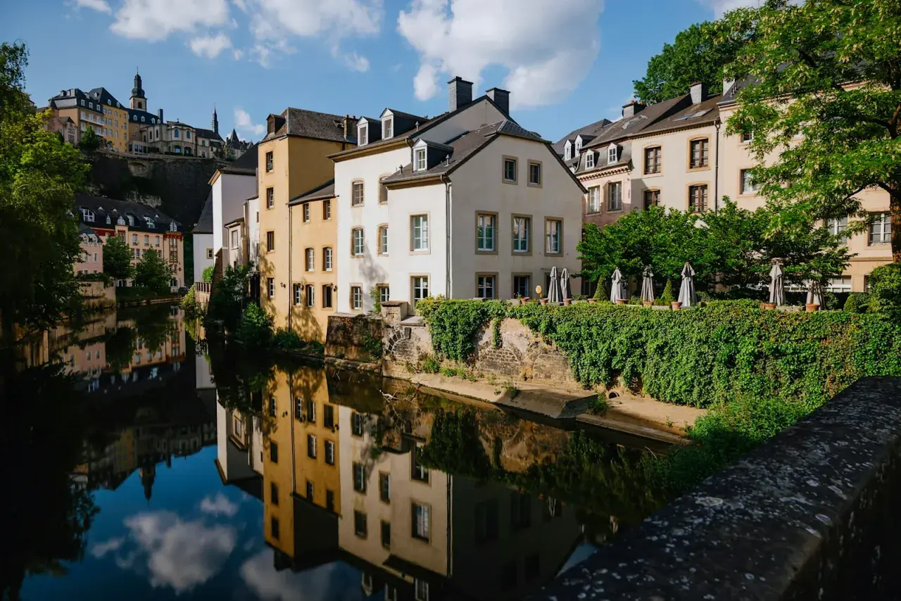 Vackra hus längs en flod i Luxemburgs huvudstad, med speglingar i vattnet.