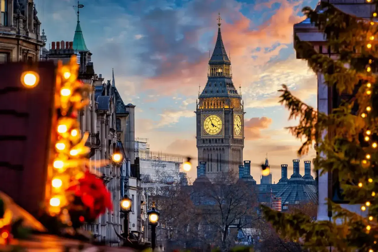 Big Ben lyser upp en magisk london julmarknad. Julgranar med ljus och vackra byggnader skapar en festlig stämning i solnedgången.
