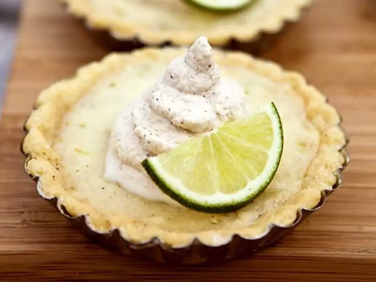 En liten key lime pie med en klick grädde och en limeklyfta.