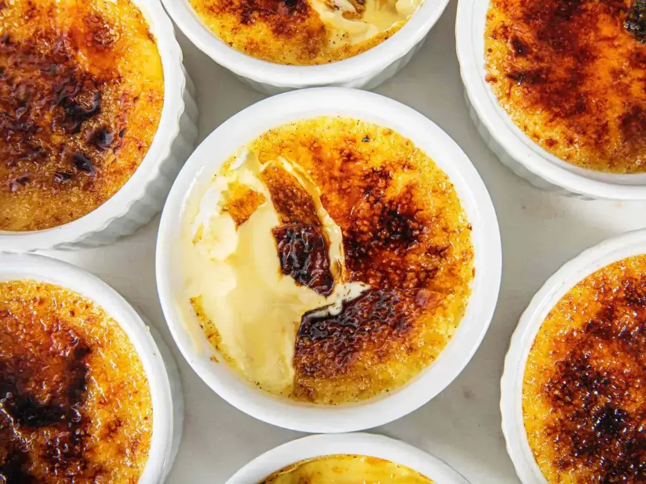 Flera krämiga creme brulee-desserter med karamelliserat sockerlock.
