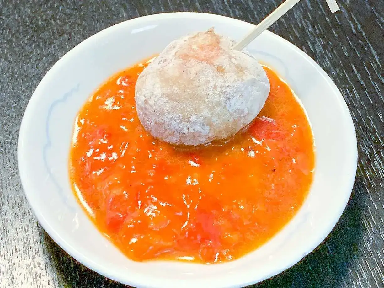 En boll med en tandpetare i en sk&aring;l med r&ouml;d s&aring;s, kanske en smak av mojo rojo.