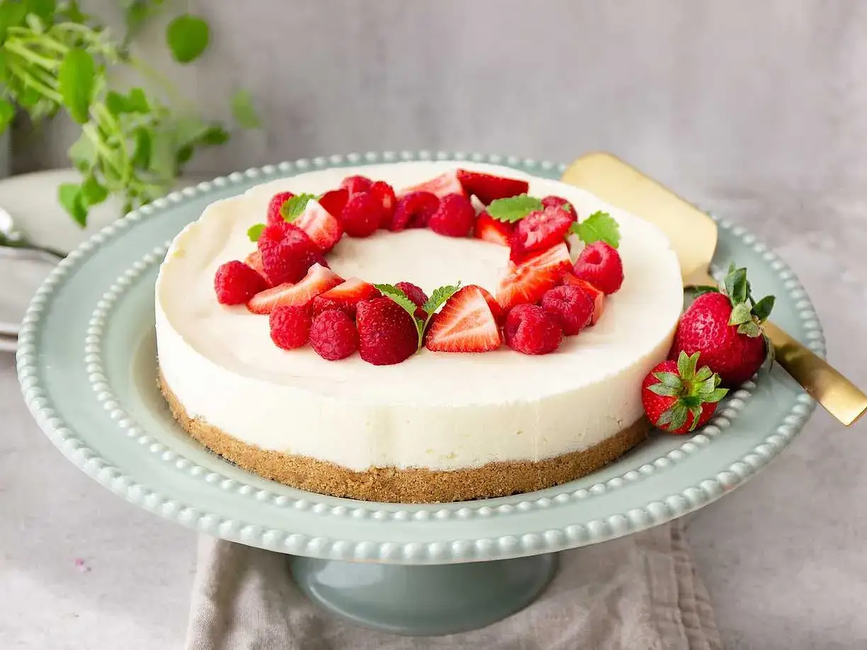 En kr&auml;mig frozen cheesecake med f&auml;rska hallon och jordgubbar, perfekt f&ouml;r en sommarfest.