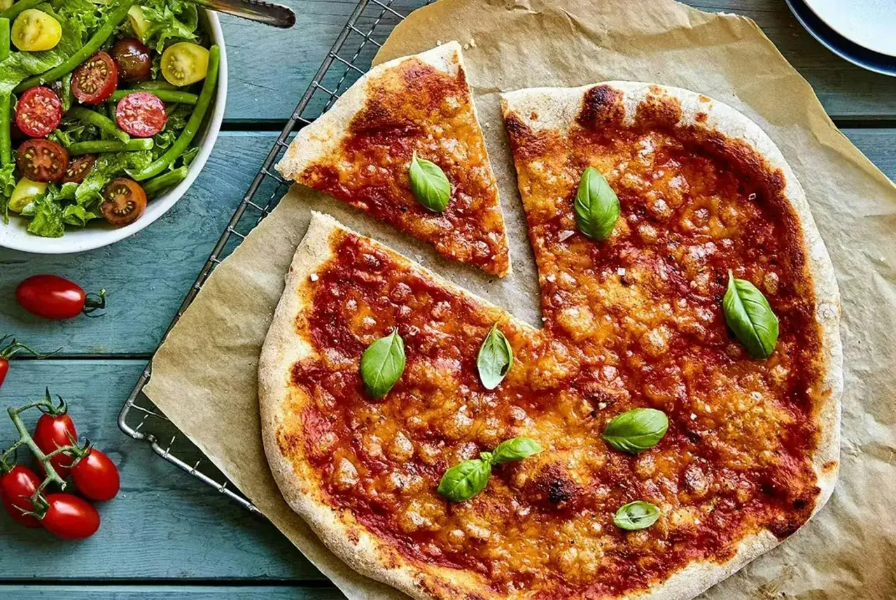 En saftig hemgjord pizza med tomats&aring;s och ost, toppad med f&auml;rsk basilika. Bredvid en fr&auml;sch sallad med gr&ouml;na b&ouml;nor och k&ouml;rsb&auml;rstomater. Ett perfekt hemgjord pizza recept f&ouml;r en h&auml;rlig m&aring;ltid.
