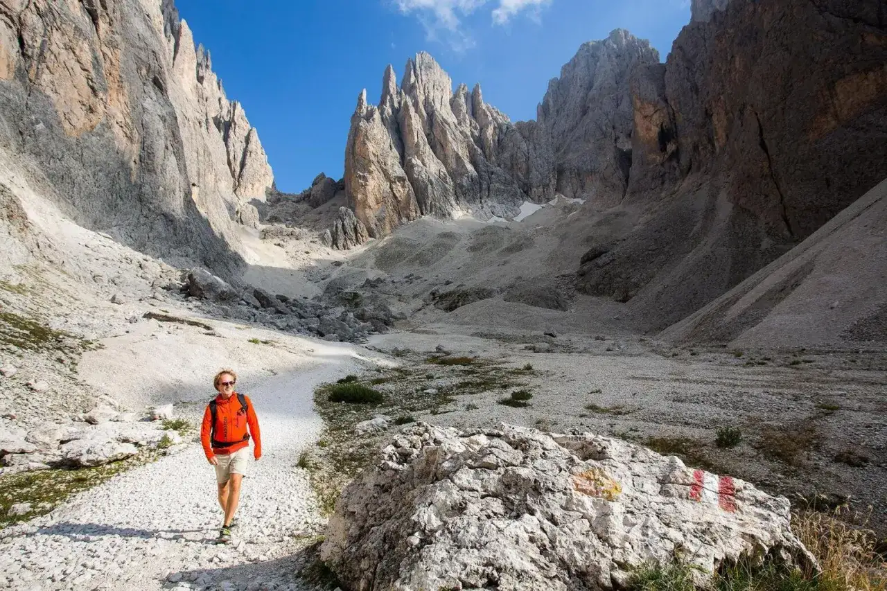 Vandrare i Dolomiterna Italien, omgiven av dramatiska bergstoppar och en grusig stig.