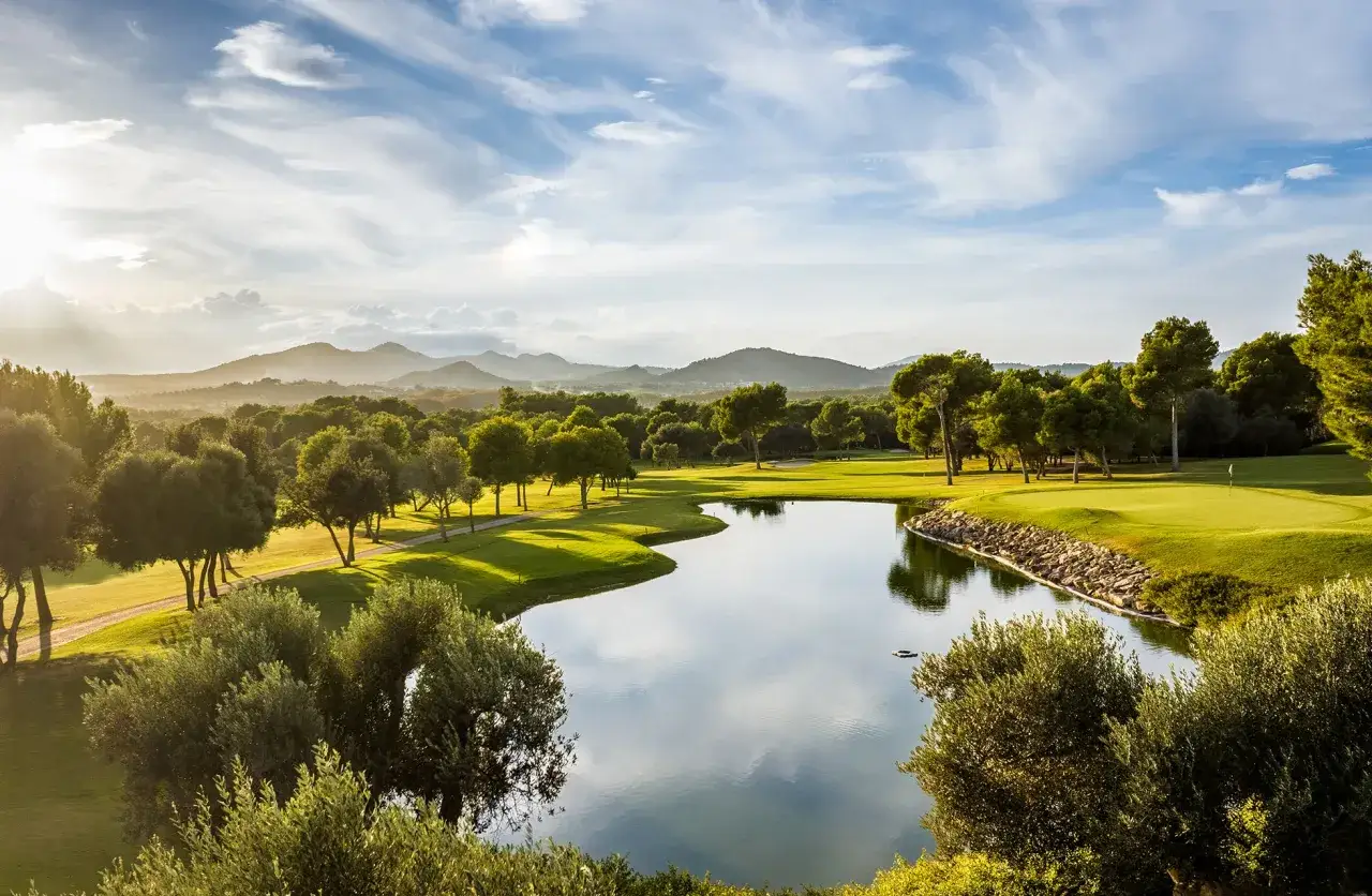 Vacker golfbana med sj&ouml; och berg i bakgrunden, perfekt f&ouml;r en golfhelg i Spanien.