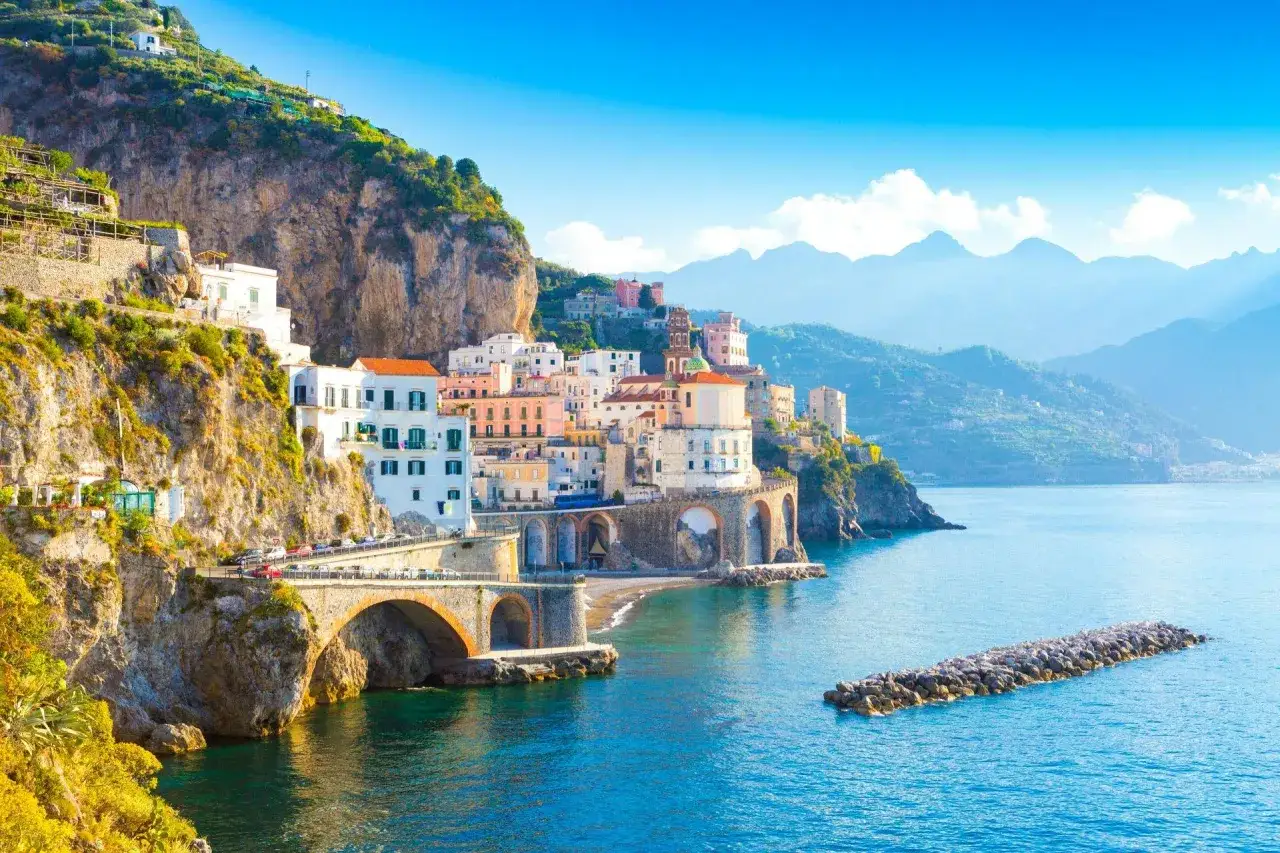 F&auml;rgstarka hus kl&auml;ttrar uppf&ouml;r klipporna vid Sorrentohalv&ouml;n, med broar som sp&auml;nner &ouml;ver havet.