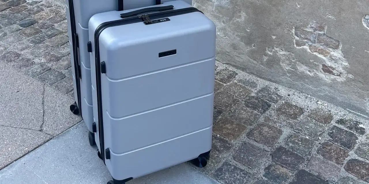 Tv&aring; gr&aring; resv&auml;skor, varav en &auml;r ett perfekt m&aring;tt handbagage, st&aring;r p&aring; en kullerstensbelagd trottoar.