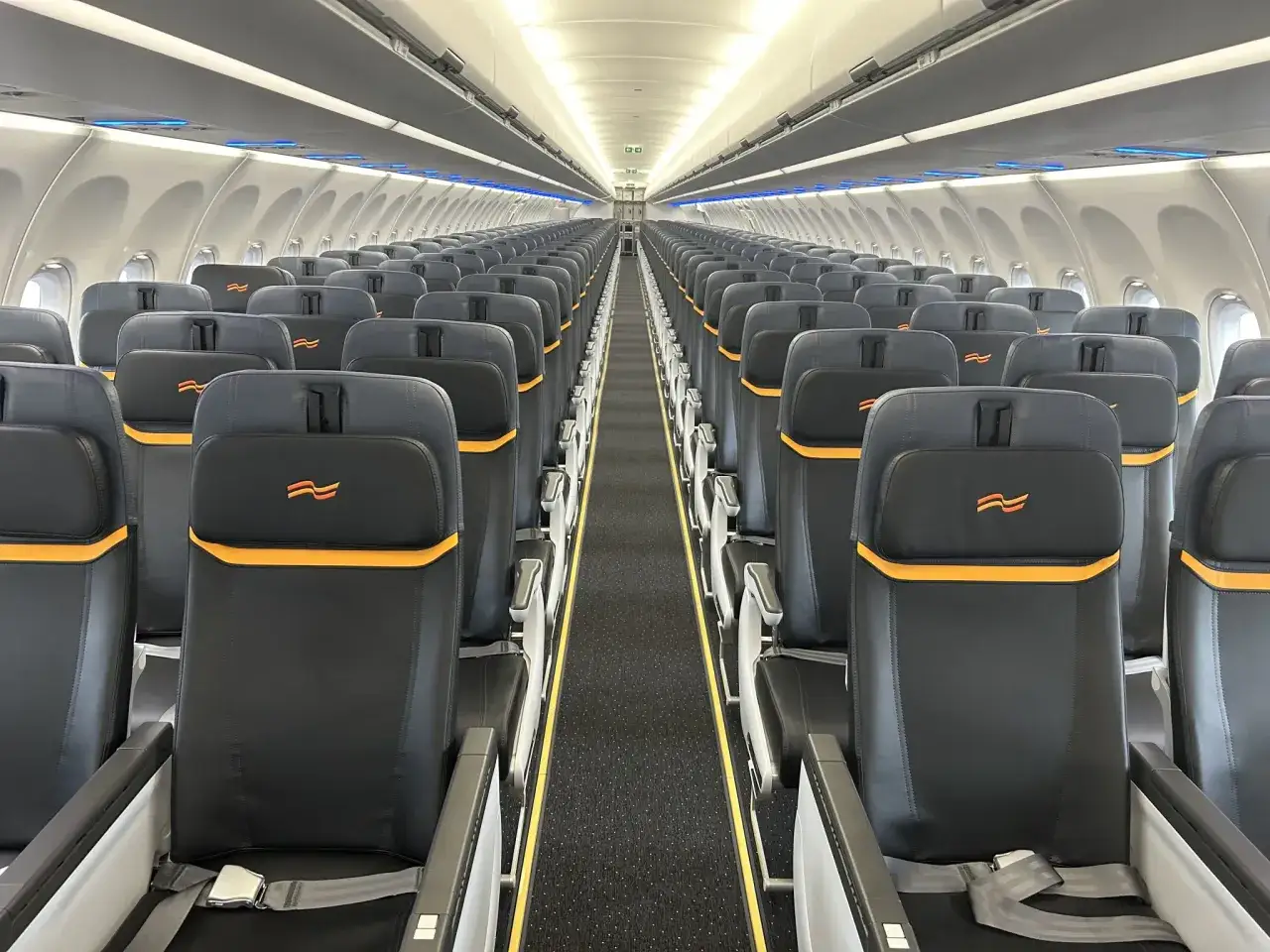 Tomma s&auml;ten i ett flygplan med ving logotyp. En l&aring;ng g&aring;ng leder mot flygplanets bakre del, redo f&ouml;r passagerare med detta ving flygbolag.