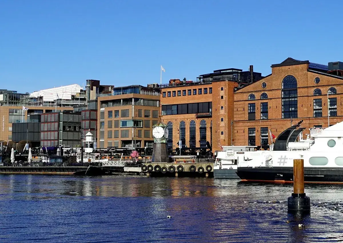 En del av Oslo med moderna byggnader och en historisk klocka vid vattnet.