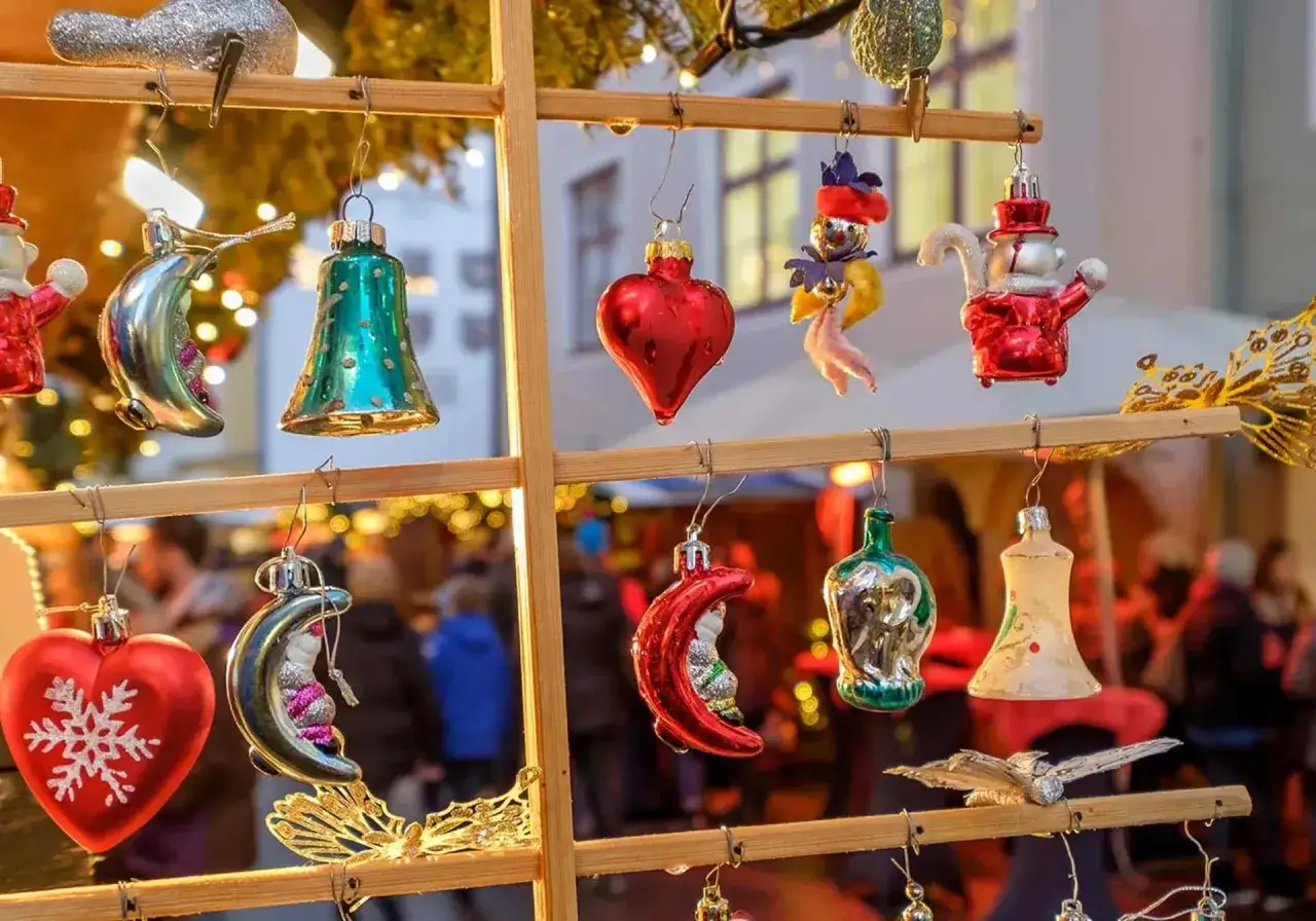 Julmarknad i Berlin: H&auml;ngande julgranskulor i form av hj&auml;rtan, m&aring;nar och klockor. I bakgrunden syns folk och ljus.