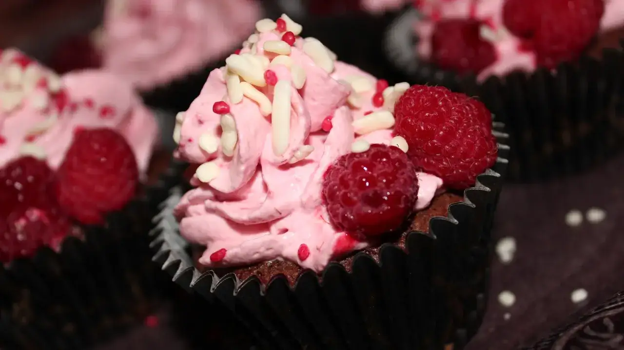 Kladdkakemuffins med rosa frosting, hallon och str&ouml;ssel. Perfekt f&ouml;r ett kladdkakemuffins recept!