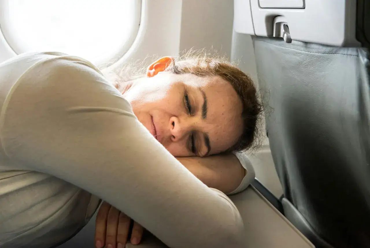 Kvinna sover p&aring; ett flygplan, troligen drabbad av jetlag usa till sverige.