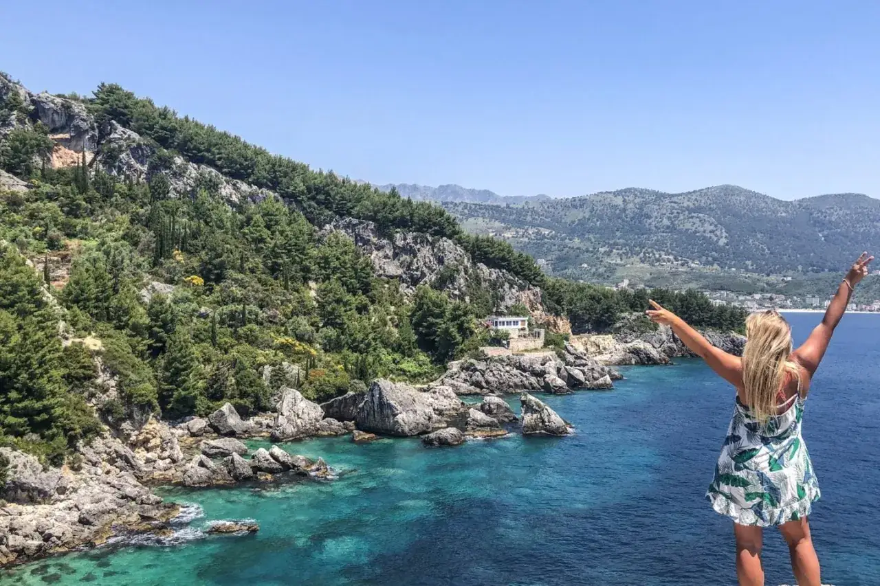 Glad turist i Albanien njuter av den turkosa kusten och bergen.
