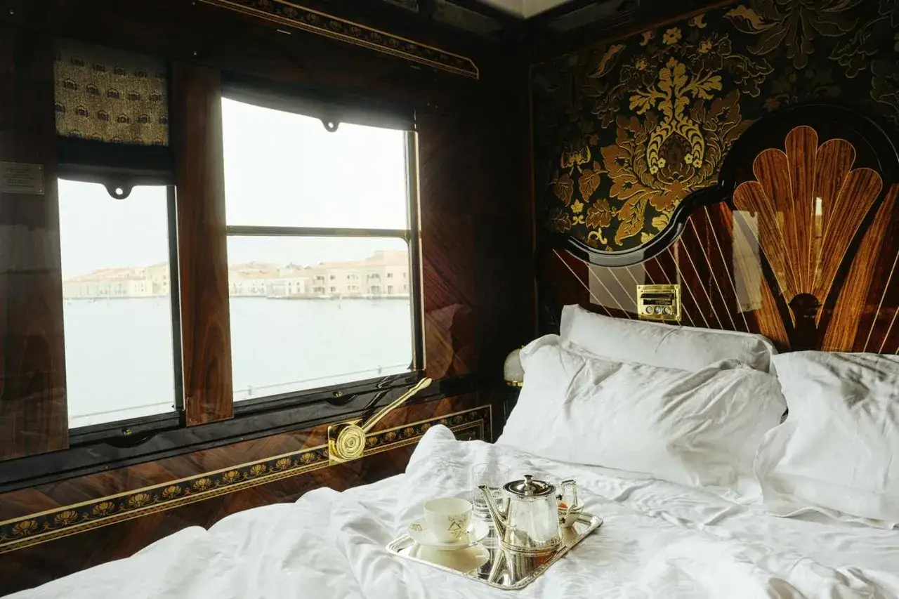 Lyxiga t&aring;gresor Europa: En elegant kup&eacute; med utsikt &ouml;ver Venedig. Vita lakan, silverbricka med te och en uts&ouml;kt inredning.