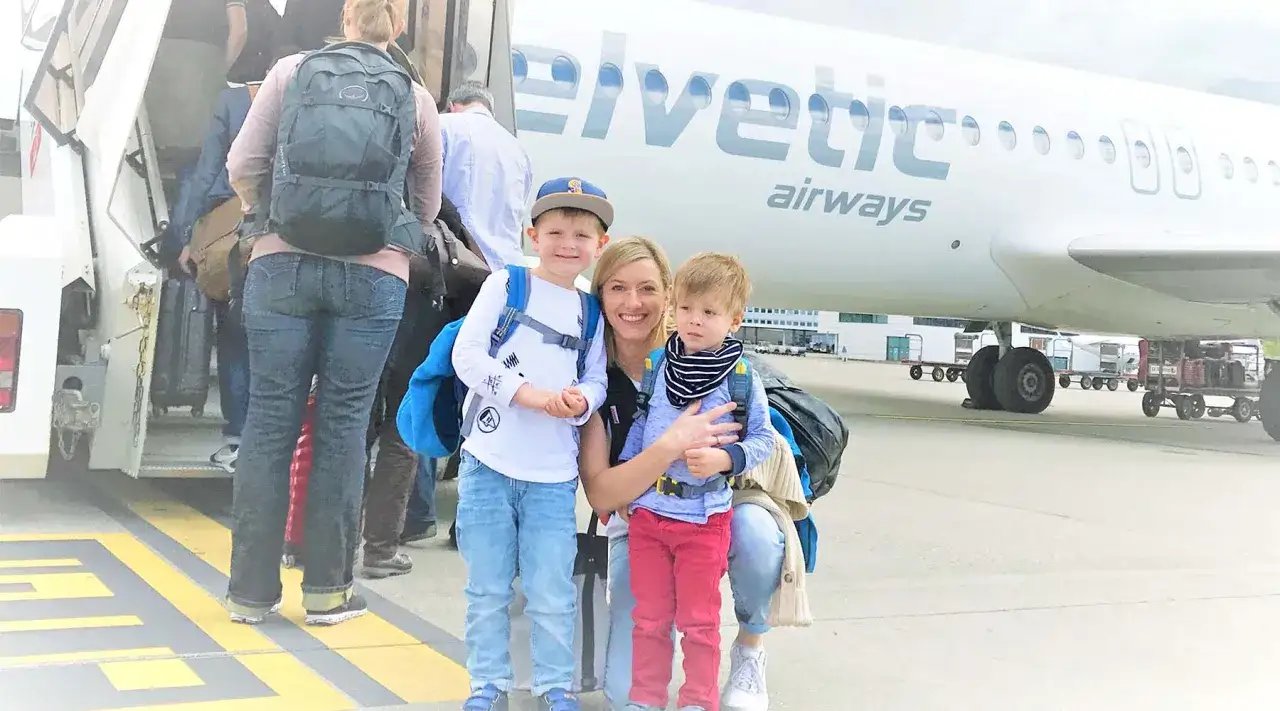 Glad familj redo att flyga med barn. Ett &auml;ventyr v&auml;ntar vid Helvetic Airways flygplan.