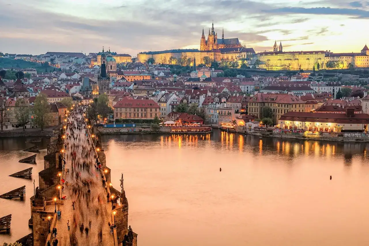En magisk kv&auml;ll p&aring; Karlsbron i Prag, perfekt f&ouml;r en weekendresa. Slottet lyser upp i bakgrunden medan folket str&ouml;mmar &ouml;ver bron.