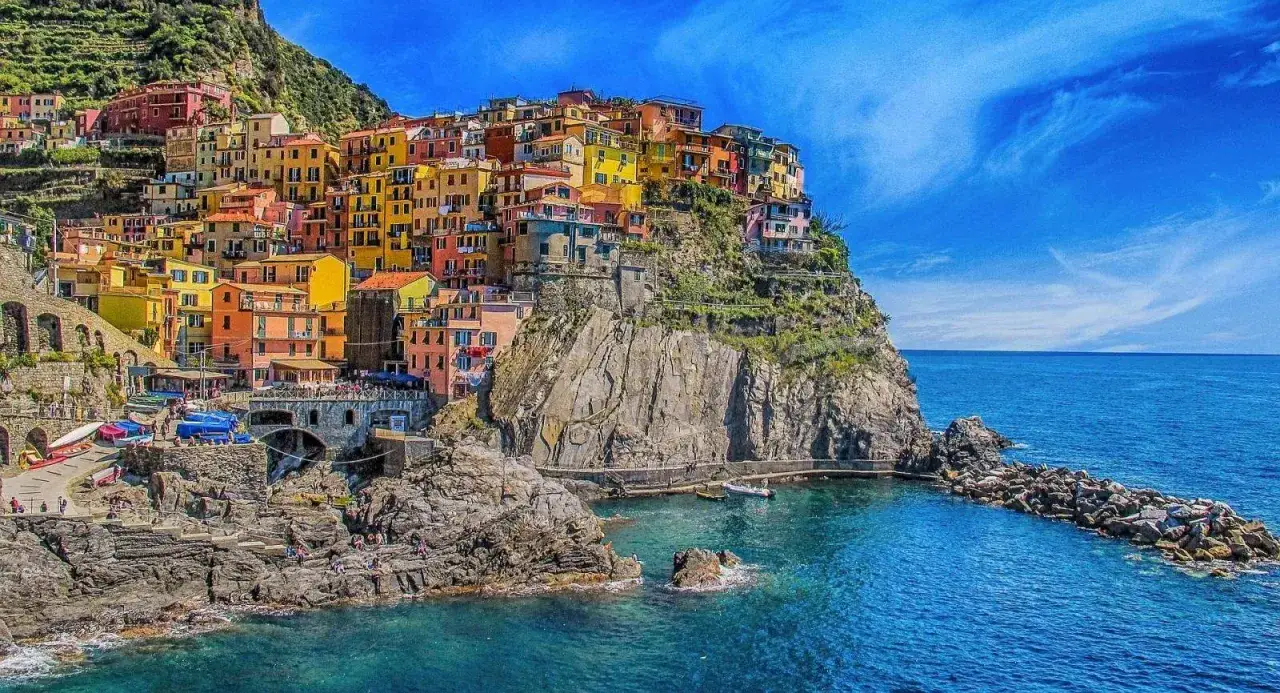 F&auml;rgglada hus kl&auml;ttrar uppf&ouml;r klipporna vid havet i Cinque Terre, 5 magiska byar.