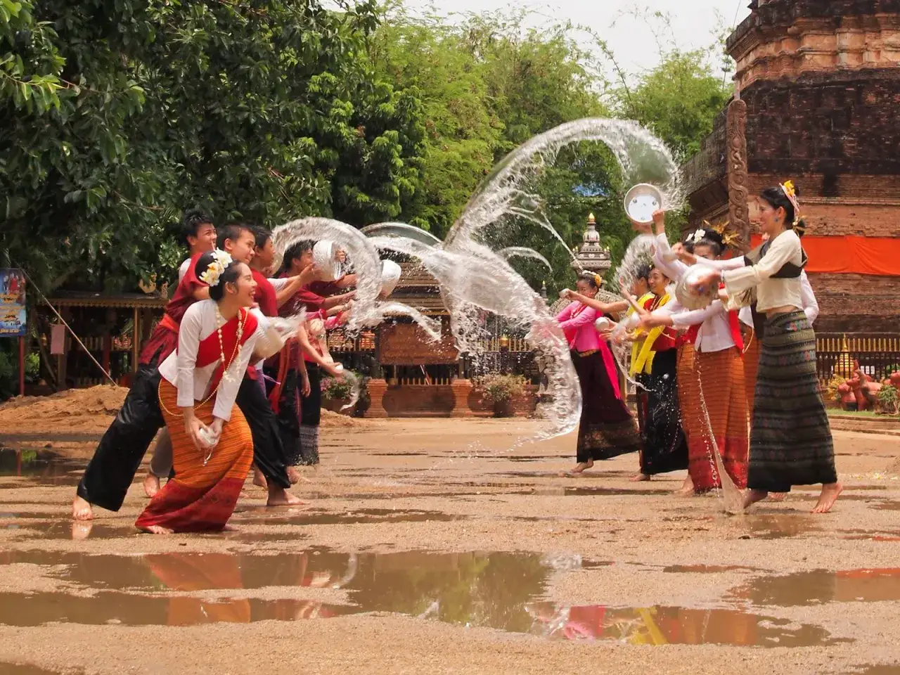 Glada m&auml;nniskor firar Songkran i Thailand med vattenkastning.