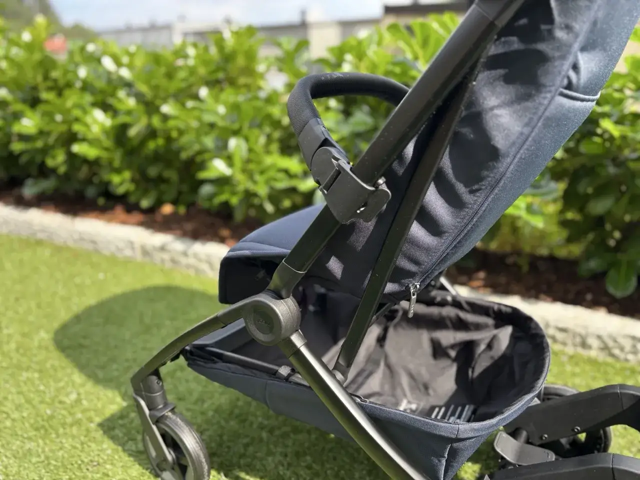 M&ouml;rkbl&aring; barnvagn med handbagage-v&auml;nlig design, redo f&ouml;r &auml;ventyr utomhus.