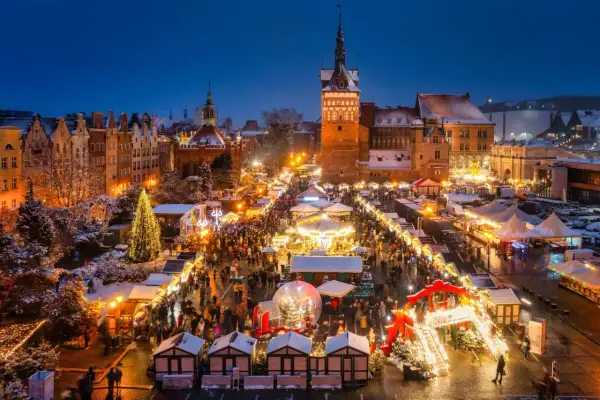 En livlig julmarknad i Gdansk med snö, julgranar och tusentals besökare som njuter av den magiska stämningen.