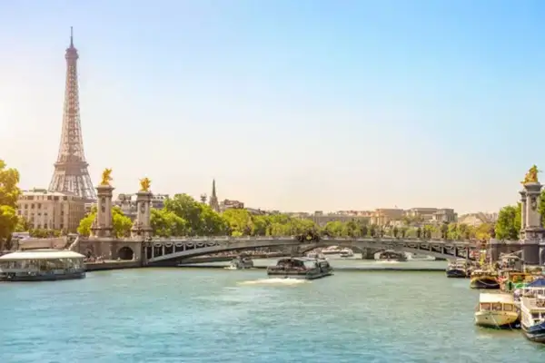 Eiffeltornet och Pont Alexandre III över Seine. En perfekt vy för en minnesvärd resa, kanske **2 dagar i Paris**? Båtar glider fram på vattnet.