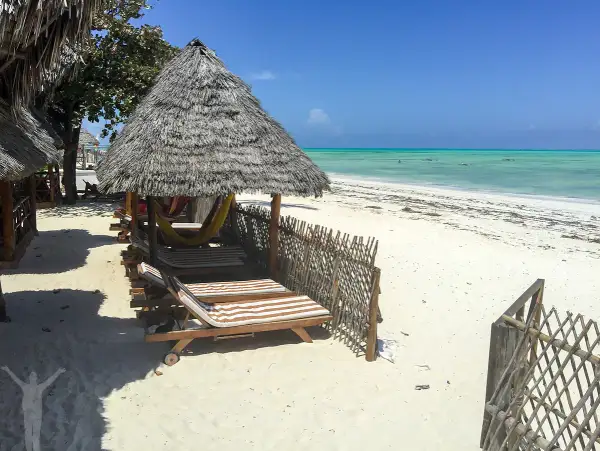 Soliga solstolar och hängmattor under halmtak vid en turkos strand. Drömmer du om en resa till Zanzibar? Pris kan variera, men detta ser ut som paradiset.