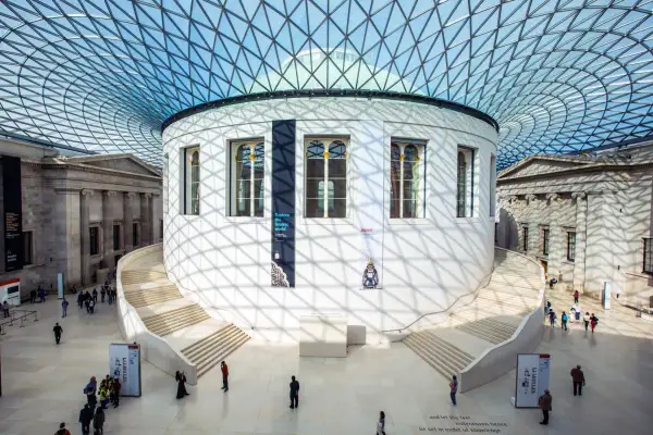 Storslagen arkitektur i London, med en imponerande glasstruktur som tak. En rund byggnad med trappor leder uppåt, omgiven av klassiska pelare. Här finns konst och historia att utforska.