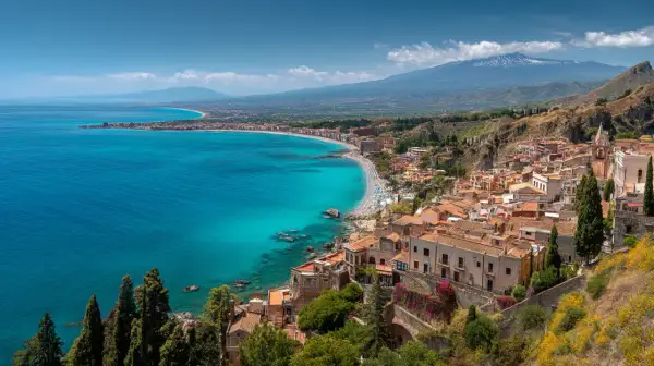 Vacker kustlinje med turkost vatten och en stad vid foten av ett berg. Siciliens storlek är imponerande, med Etna i bakgrunden.