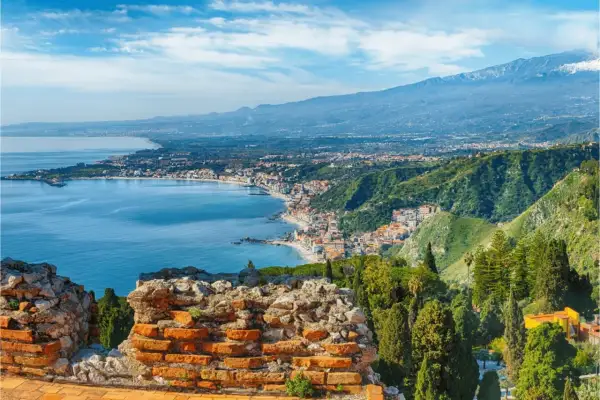 Vacker vy över kusten vid Catania, Sicilien, med det blå havet, en stad längs kusten och Etna i bakgrunden.