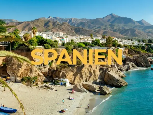 Varmast i Spanien: en solig strand med turkost vatten, klippor och vita hus i bakgrunden.