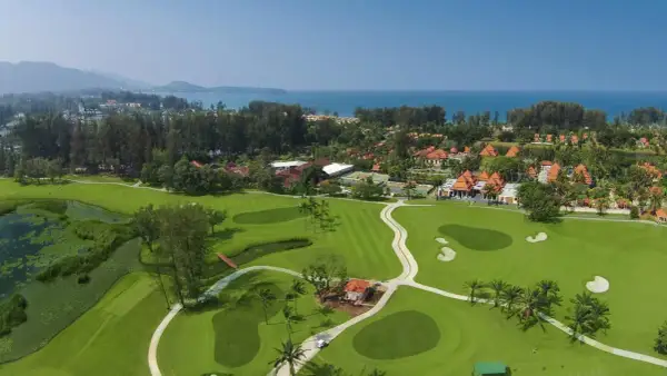 Vacker golfbana i Thailand med gröna fairways, vattenhinder och tropiska träd. En dröm för golfentusiaster.