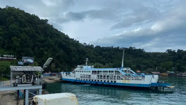 Färja anländer till Koh Chang. Gröna berg och molnigt himmel.