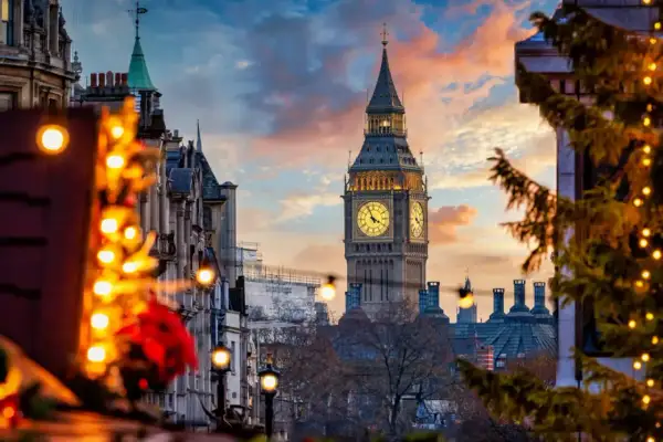 Big Ben lyser upp en magisk london julmarknad. Julgranar med ljus och vackra byggnader skapar en festlig stämning i solnedgången.