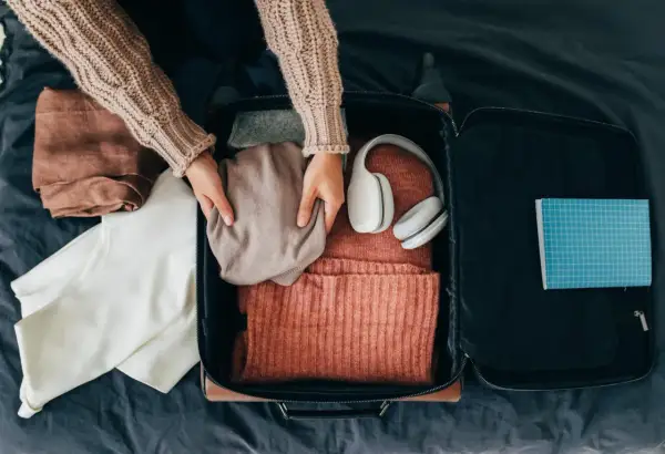 Packa smart! Här ser du vad som kan vara bra att ha i handbagaget på flyget: kläder, hörlurar och en anteckningsbok.